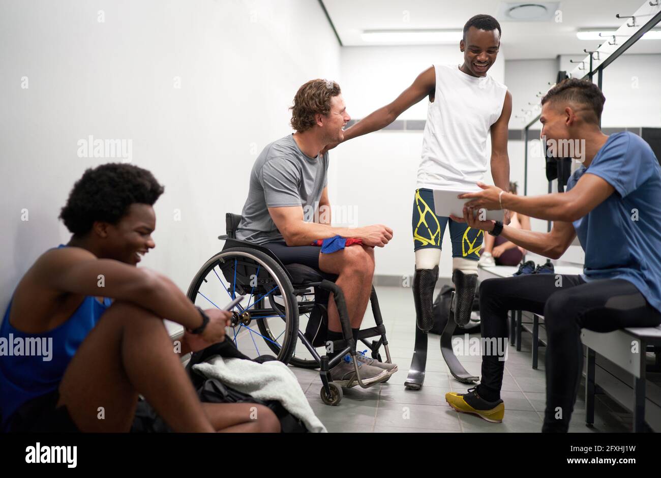 Happy male amputee and paraplegic athletes in locker room Stock Photo