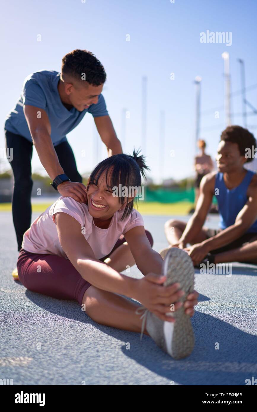 Happy young runners stretching on sunny sports track Stock Photo