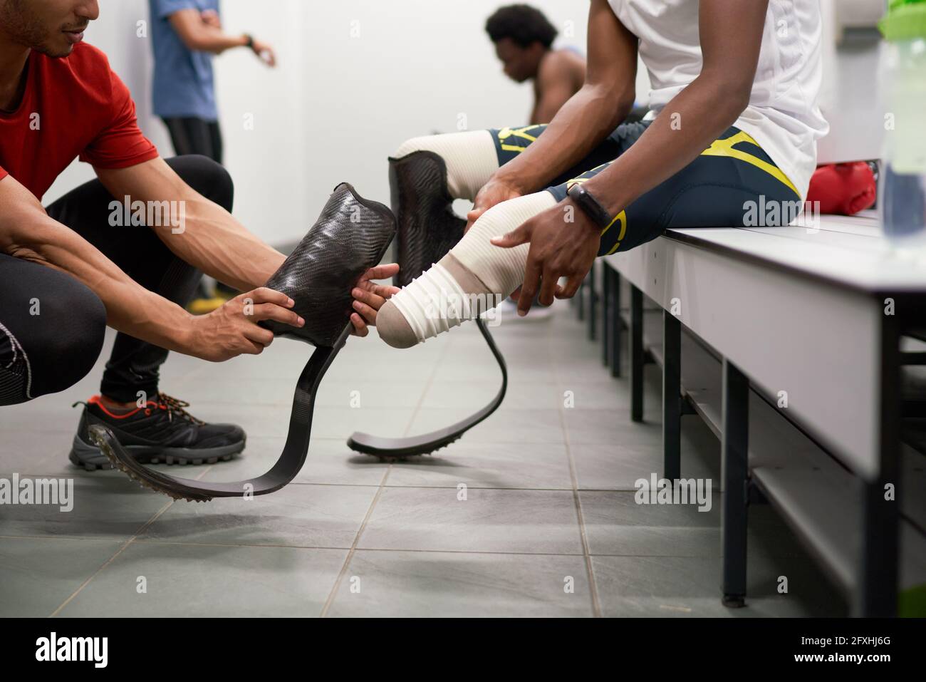 Coach helping male amputee athlete with running blade prosthetics Stock