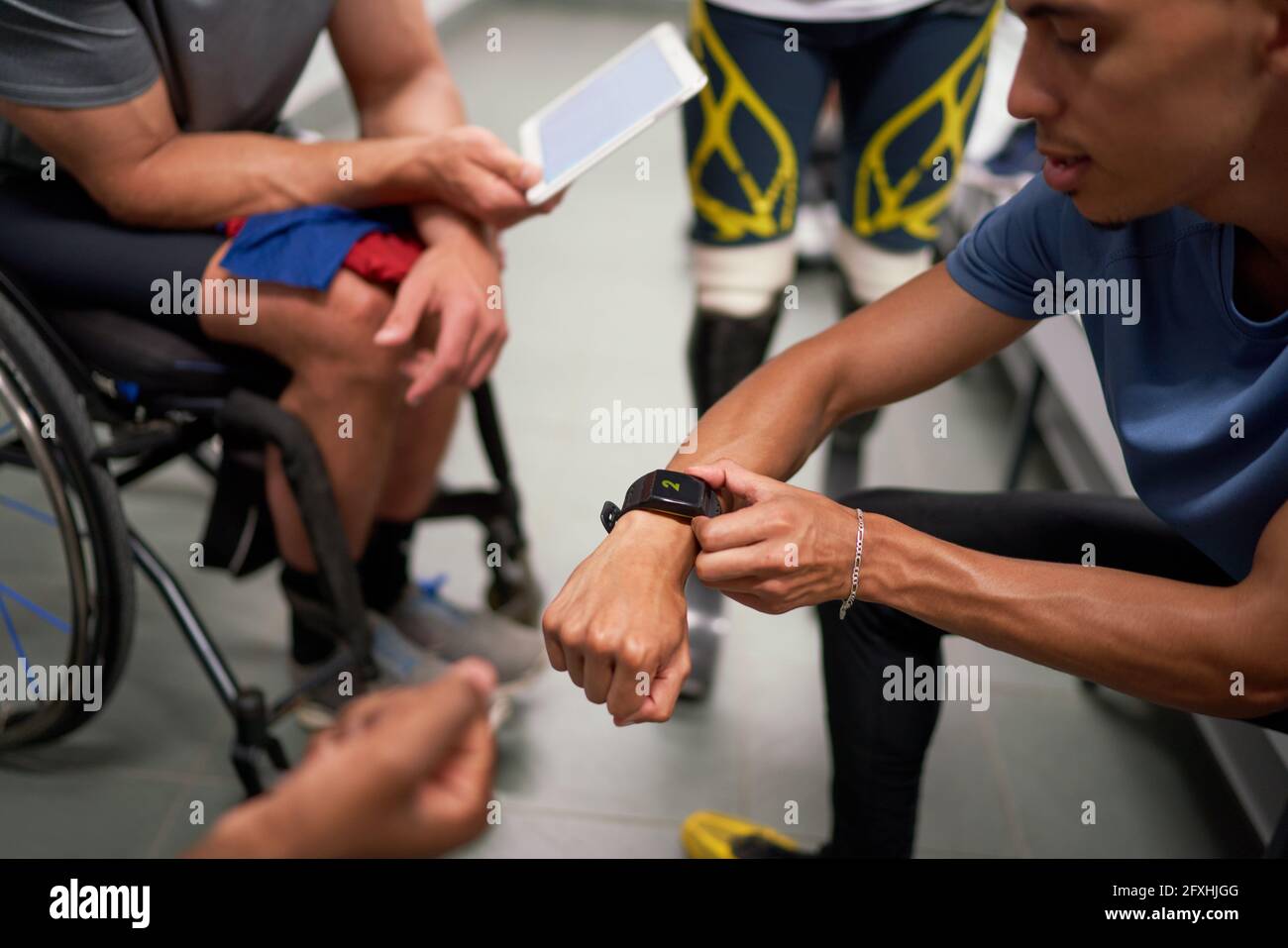 Male amputee and wheelchair athletes with smart phone in locker room Stock Photo