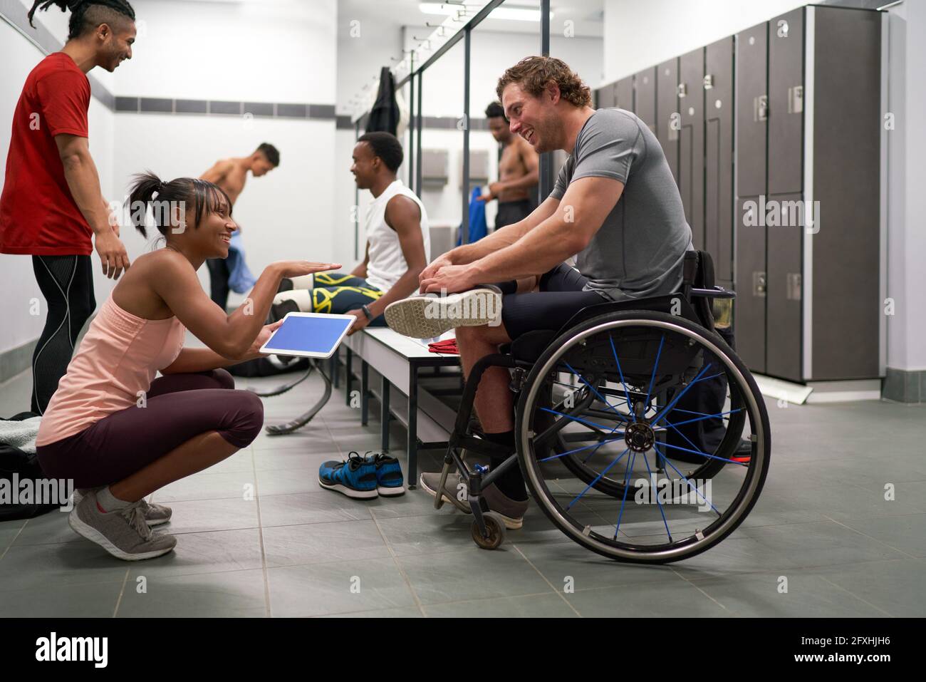 Coach and wheelchair athlete talking in locker room Stock Photo