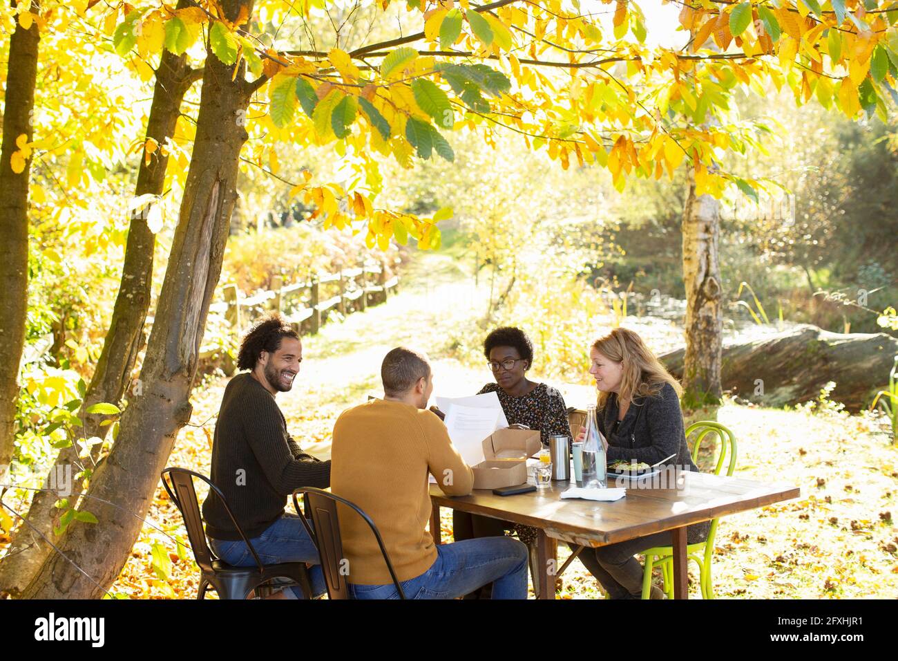 Creative business team meeting at table in sunny idyllic autumn park Stock Photo