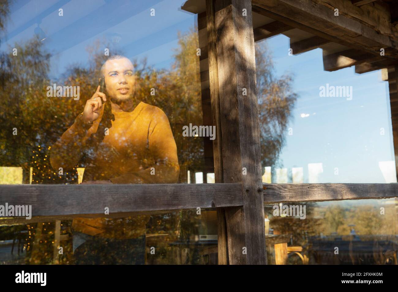 Man talking on smart phone at sunny restaurant window Stock Photo