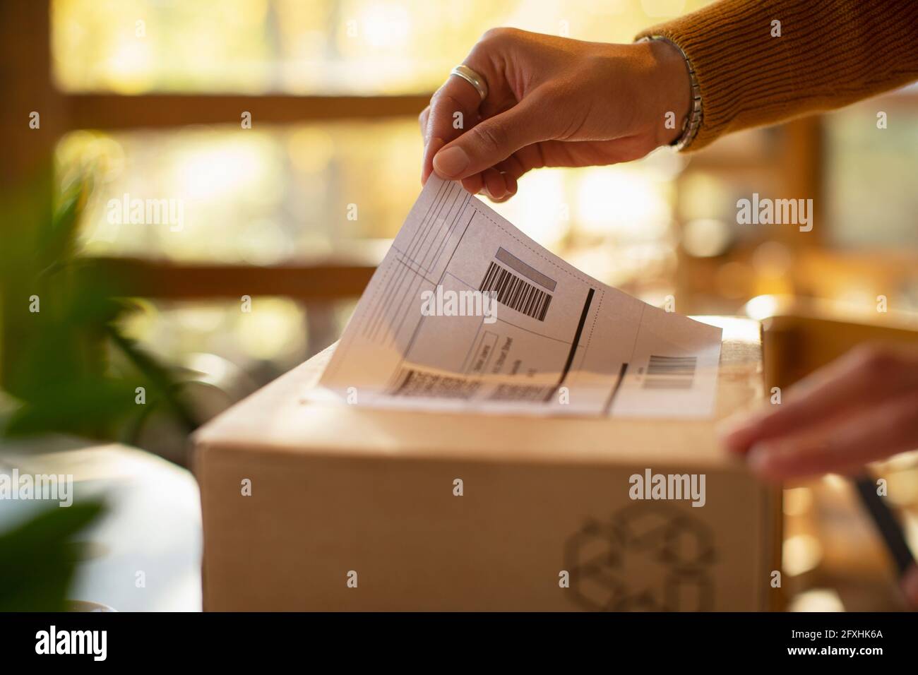 Close up business owner placing shipping label on package Stock Photo