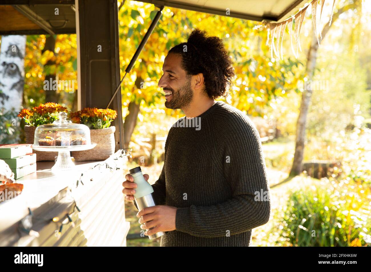 Smiling male customer ordering from food truck in autumn park Stock Photo