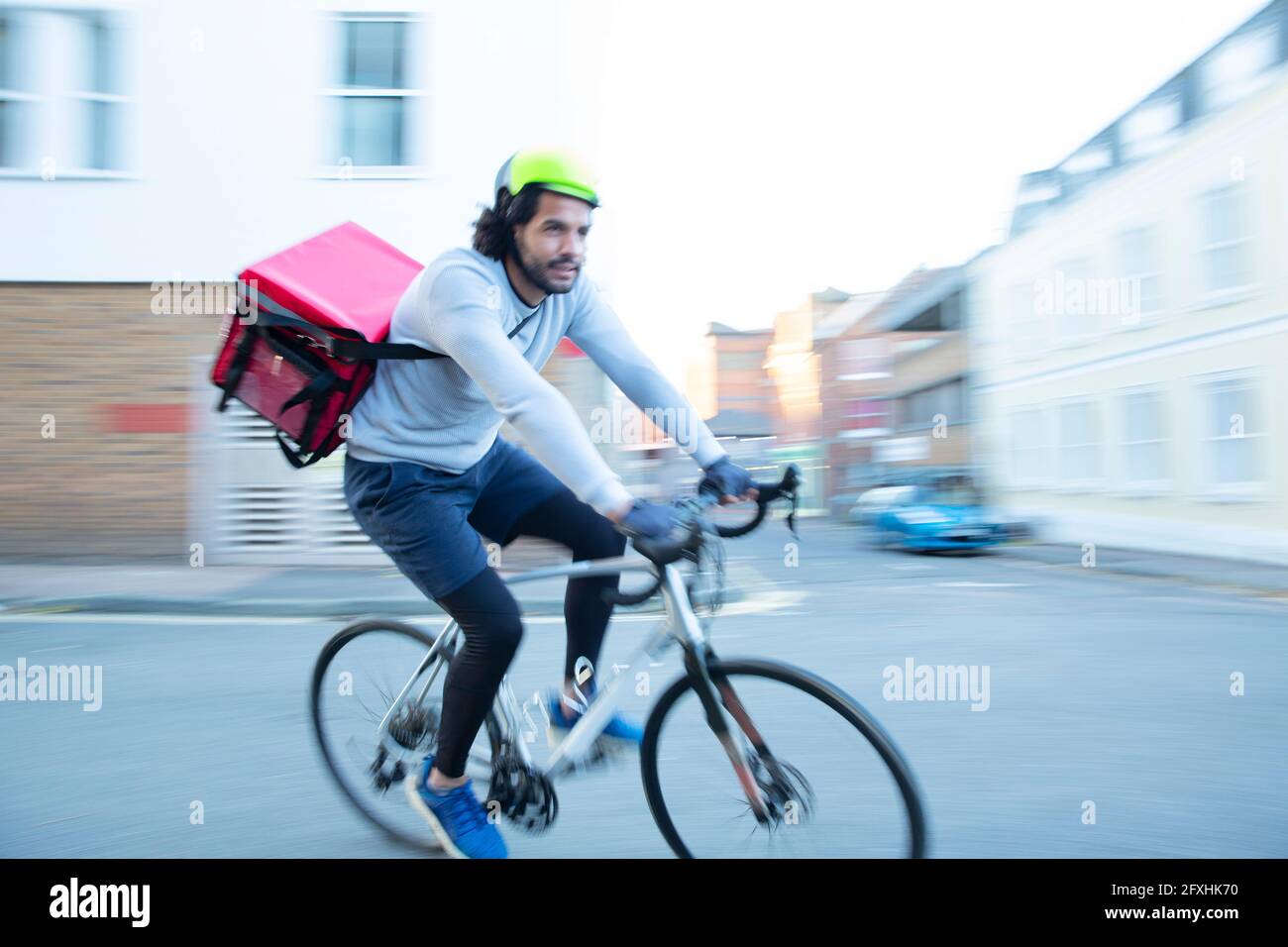 Male bike messenger delivering food on bicycle in urban neighborhood Stock Photo