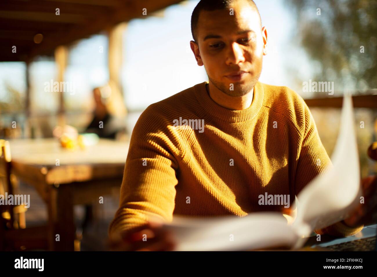 Businessman reviewing paperwork in sunny cafe Stock Photo