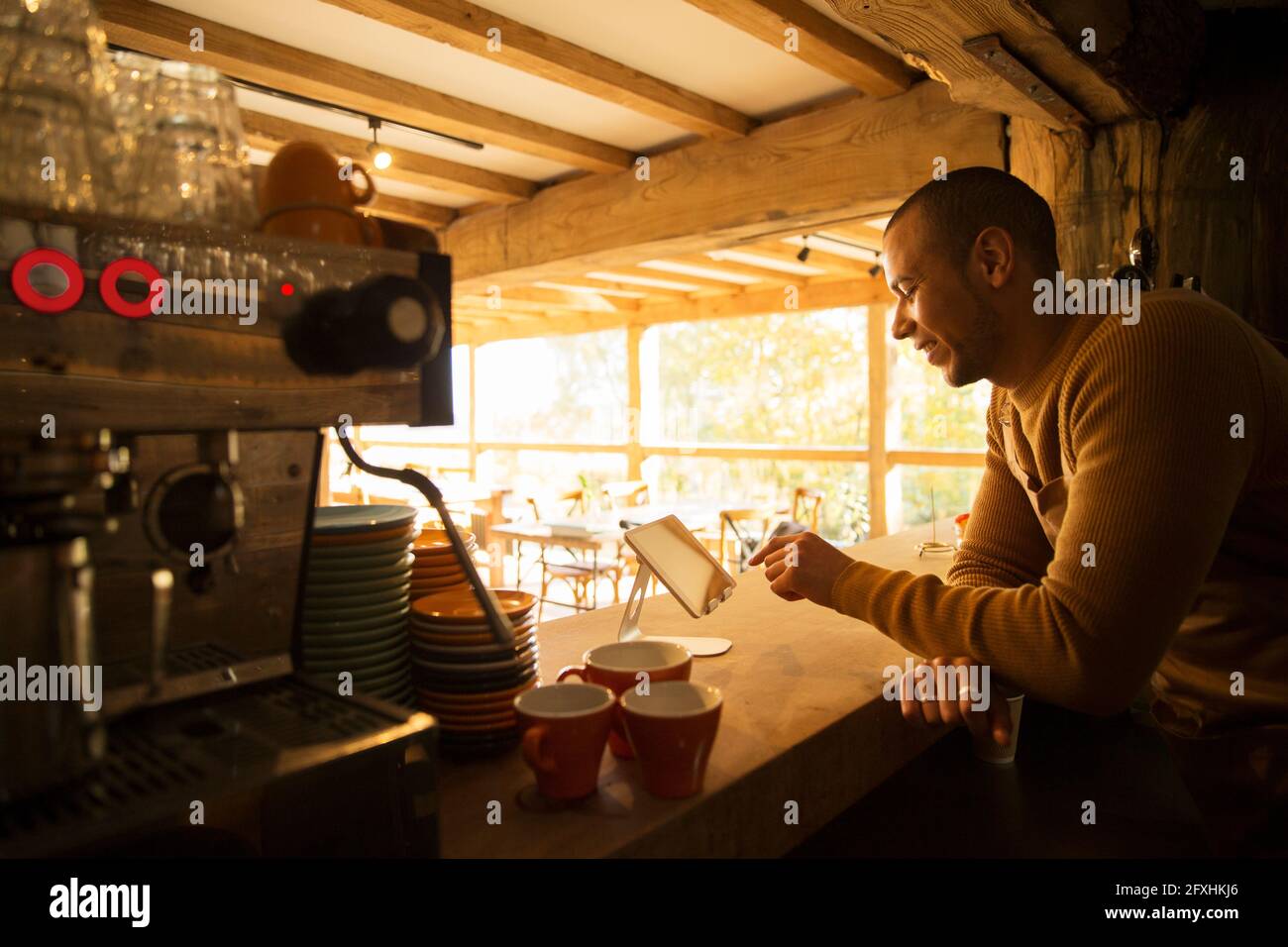 Male cafe owner using digital tablet behind counter Stock Photo
