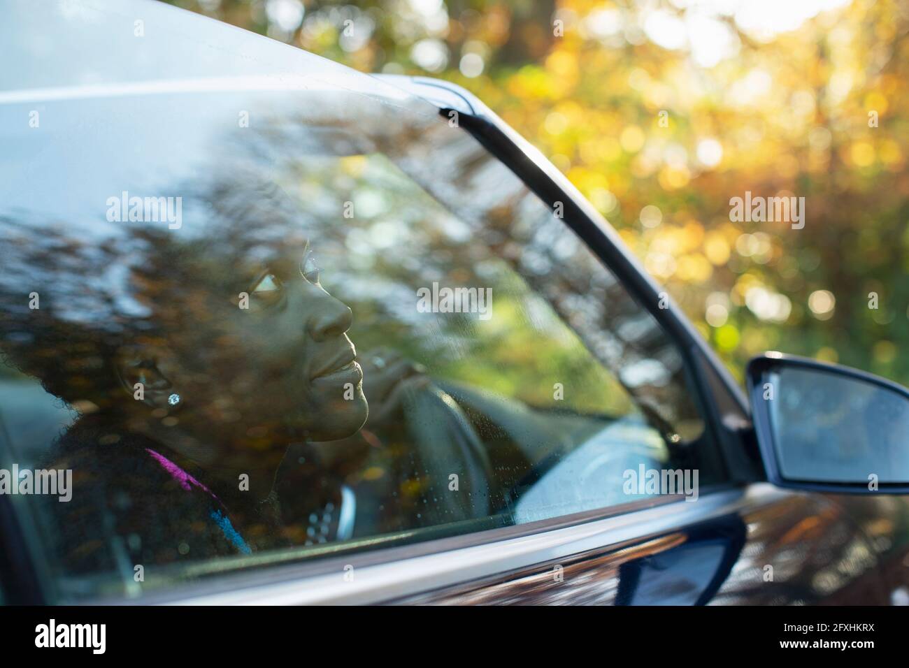 Curious woman looking out convertible window Stock Photo