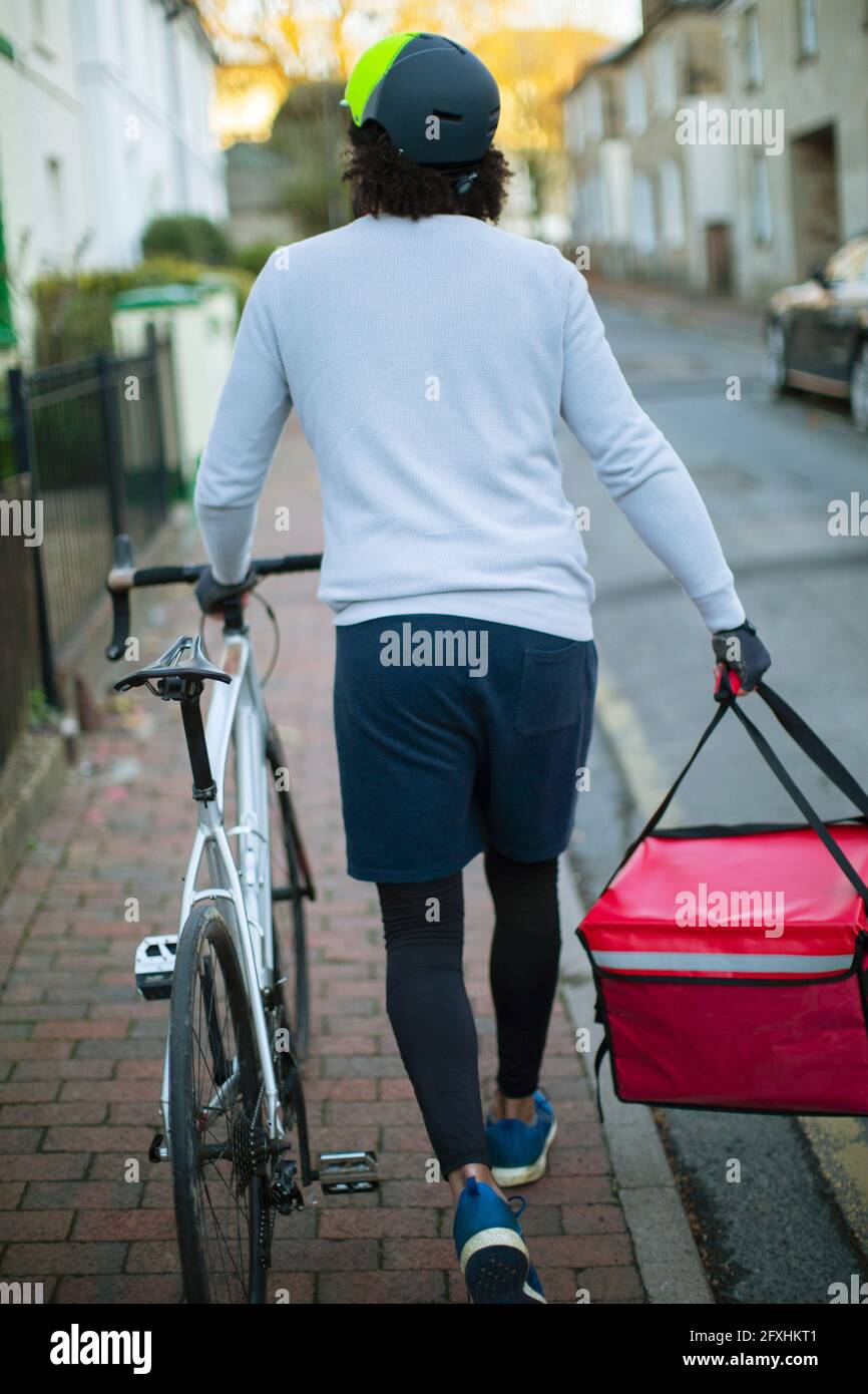 Male bike messenger delivering food in urban neighborhood Stock Photo