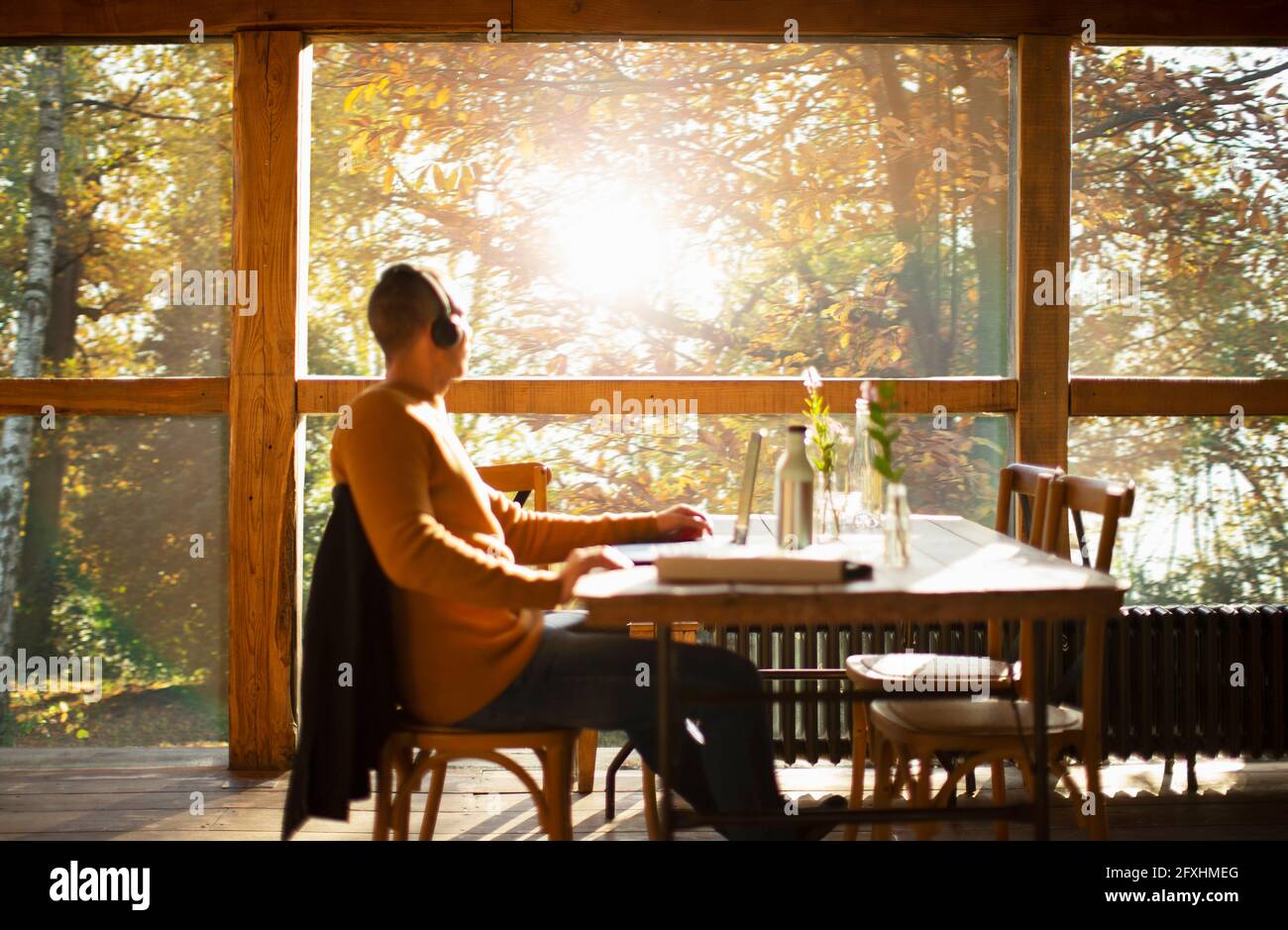 Businessman with headphones working at laptop in sunny autumn cafe Stock Photo