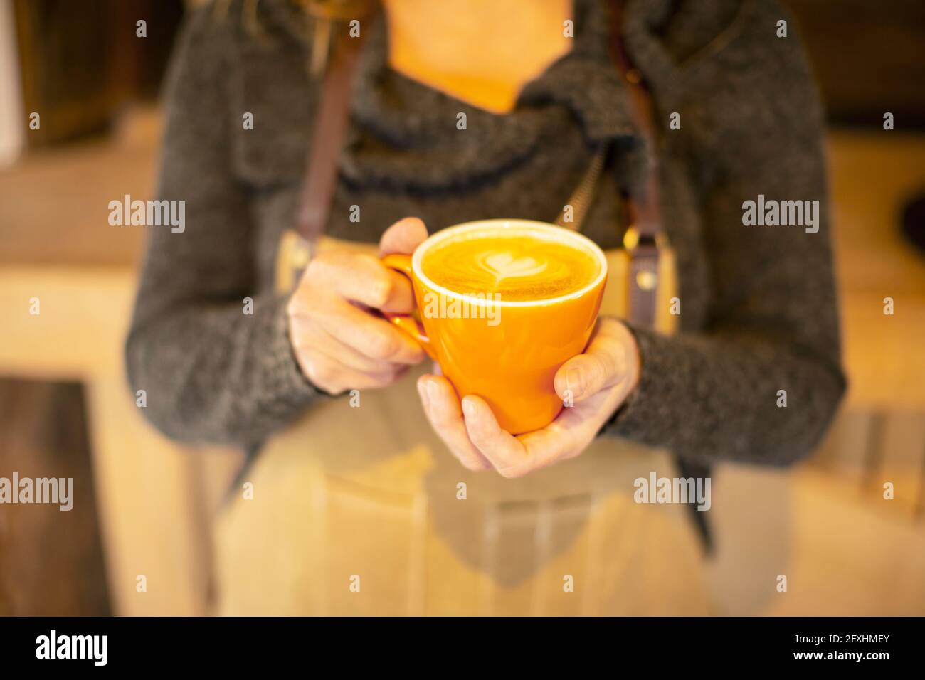 Close up female barista holding cappuccino with heart foam Stock Photo
