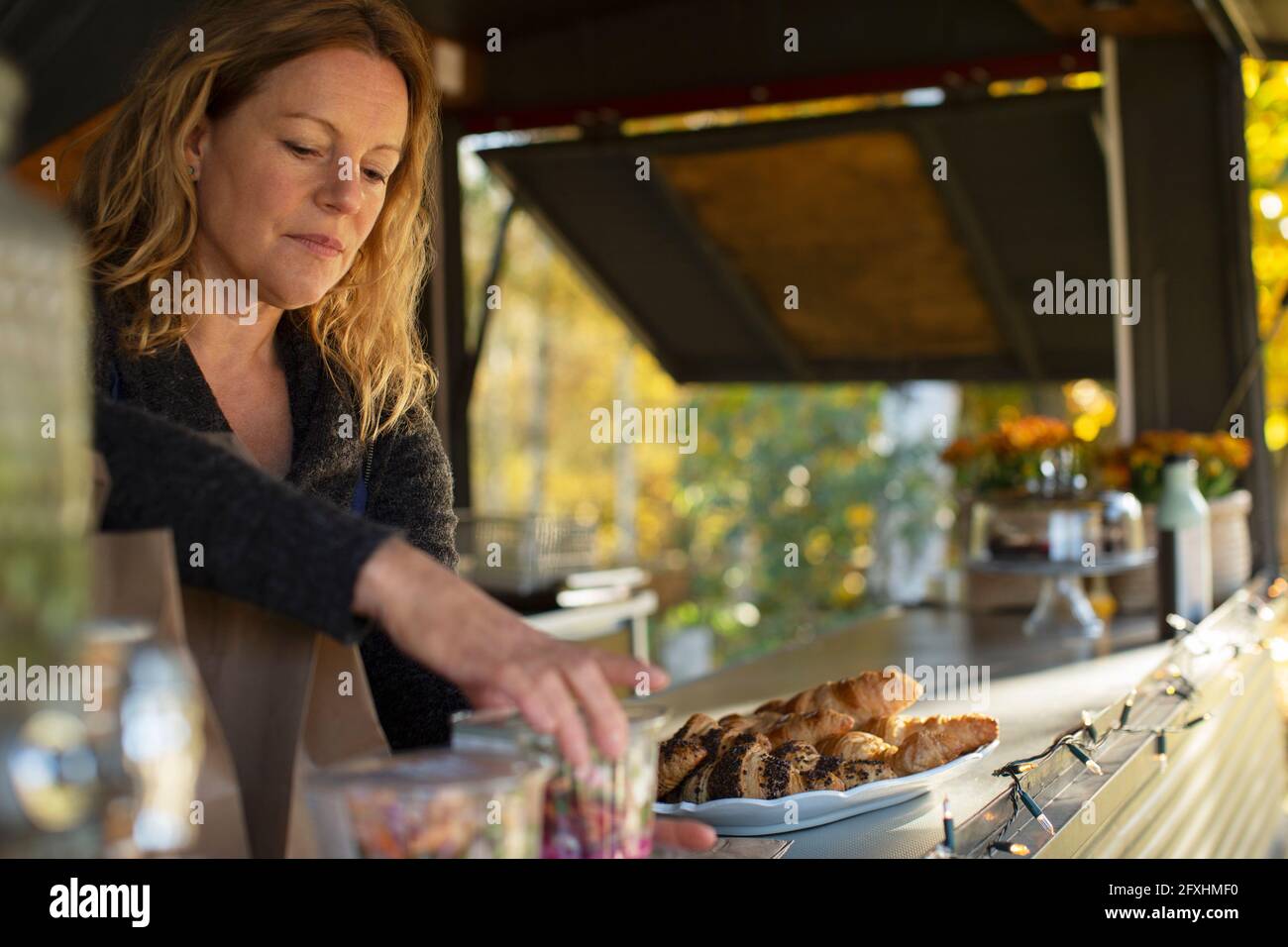 Female food cart owner arranging pastries Stock Photo