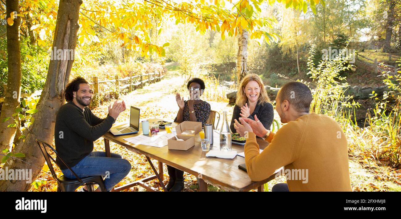 Happy business people clapping and meeting in sunny autumn park Stock Photo