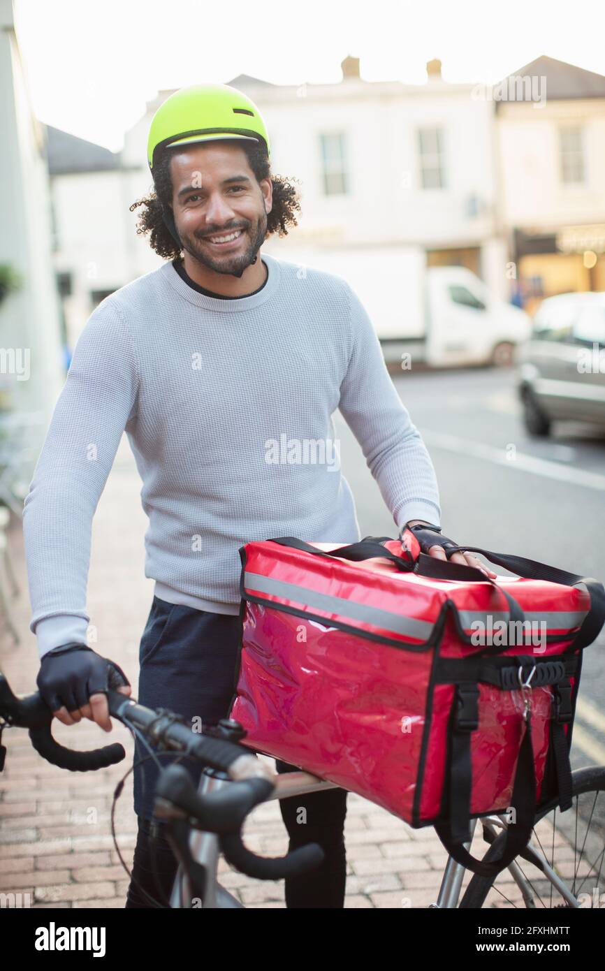 Portrait happy young male bike messenger in helmet delivering food