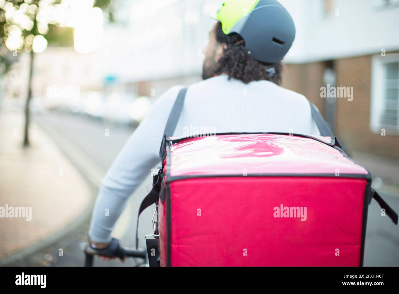 Male bike messenger in helmet delivering food on urban street Stock Photo