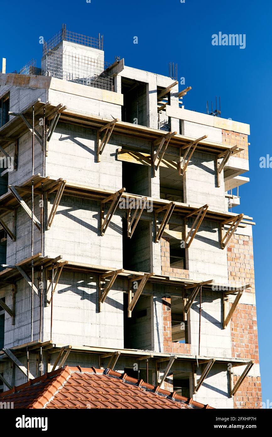 Scaffolding on the facade of an apartment building under construction against the background of a bright blue sky. Close-up Stock Photo