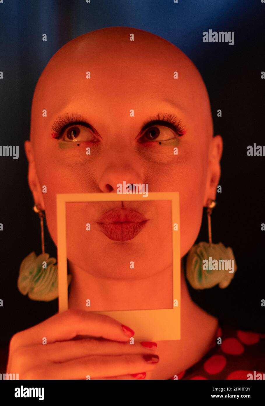 Portrait stylish woman with shaved head holding polaroid Stock Photo