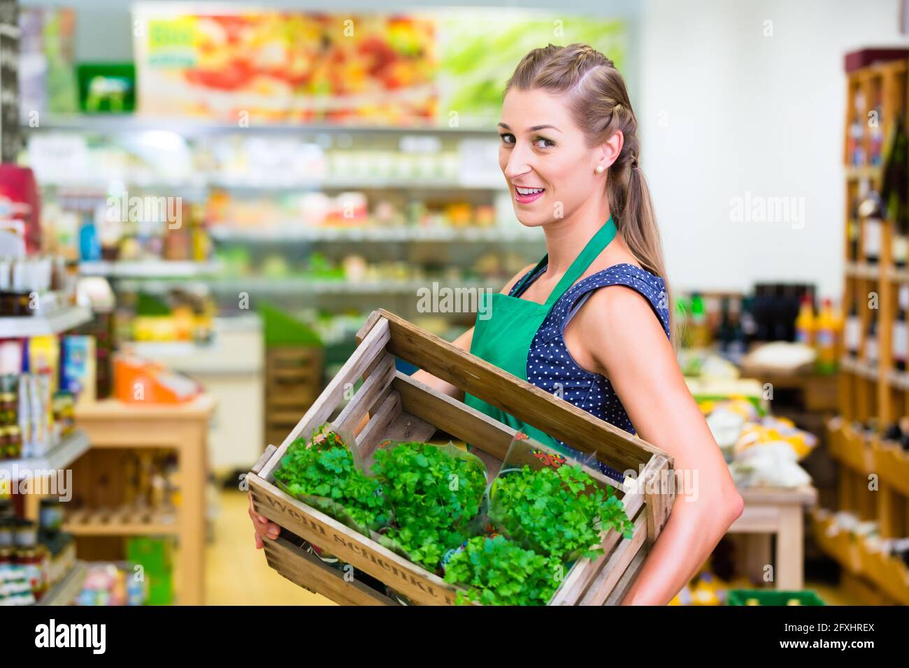 Organic Supermarket shop assistant filling up herbs storage racks in vegetable department Stock Photo