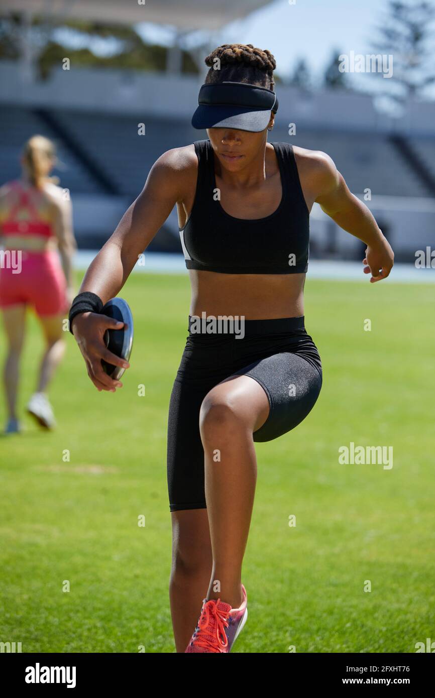 Female track and field athlete practicing discus throw in grass Stock Photo Alamy