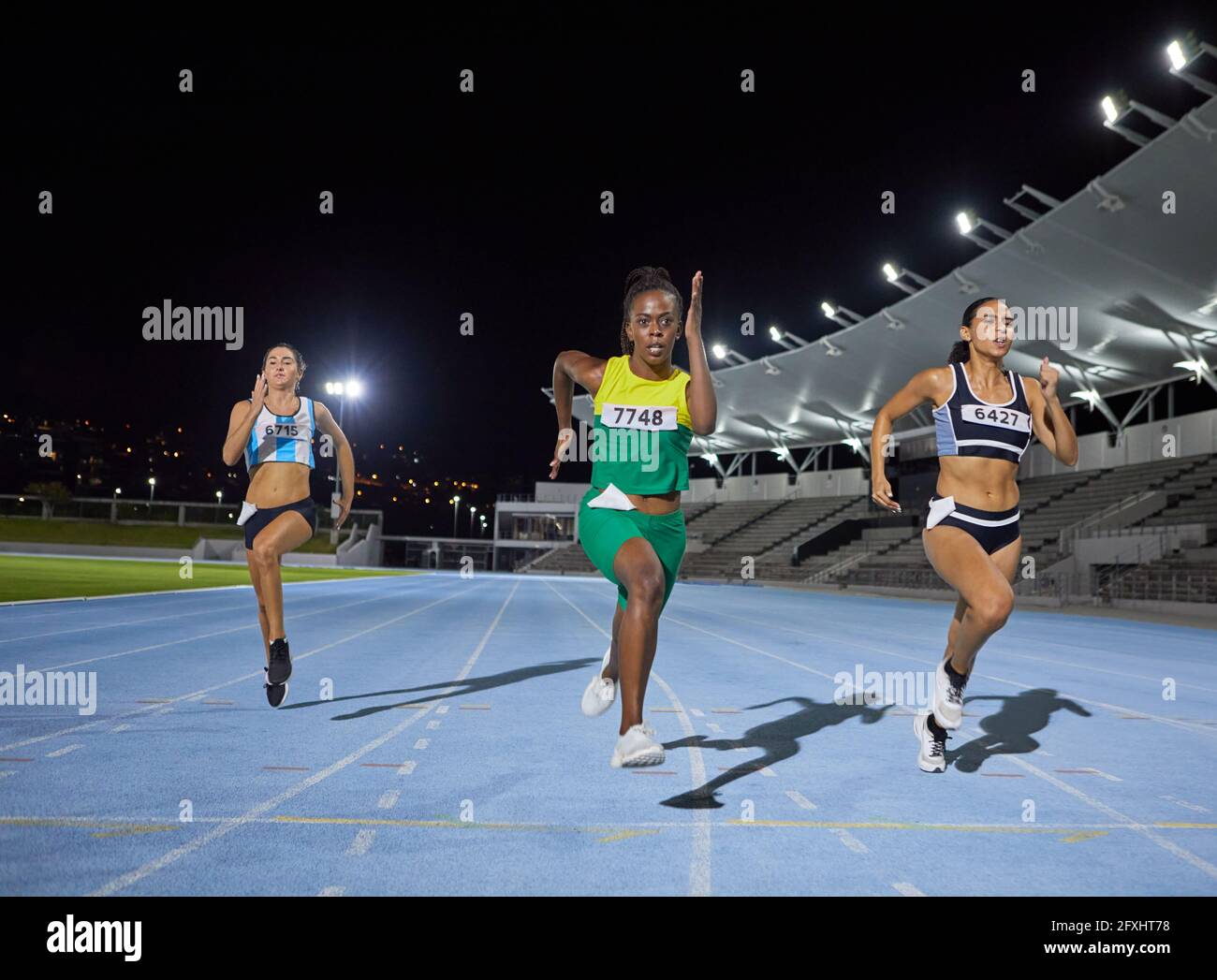 Female track and field athlete running in competition on track Stock Photo