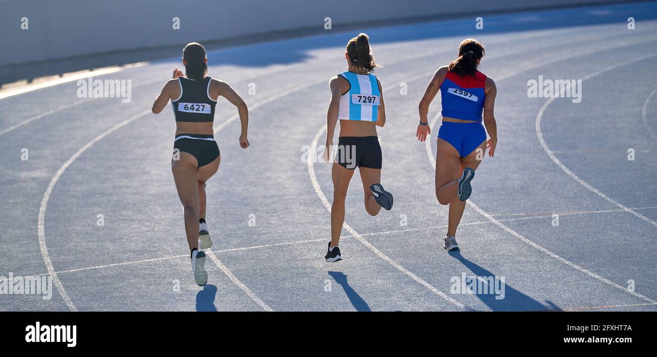 Female track and field athletes running in competition on track Stock Photo