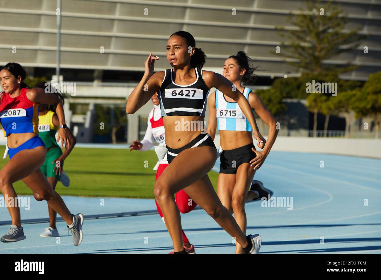 Female track and field athletes running in competition on race track Stock Photo