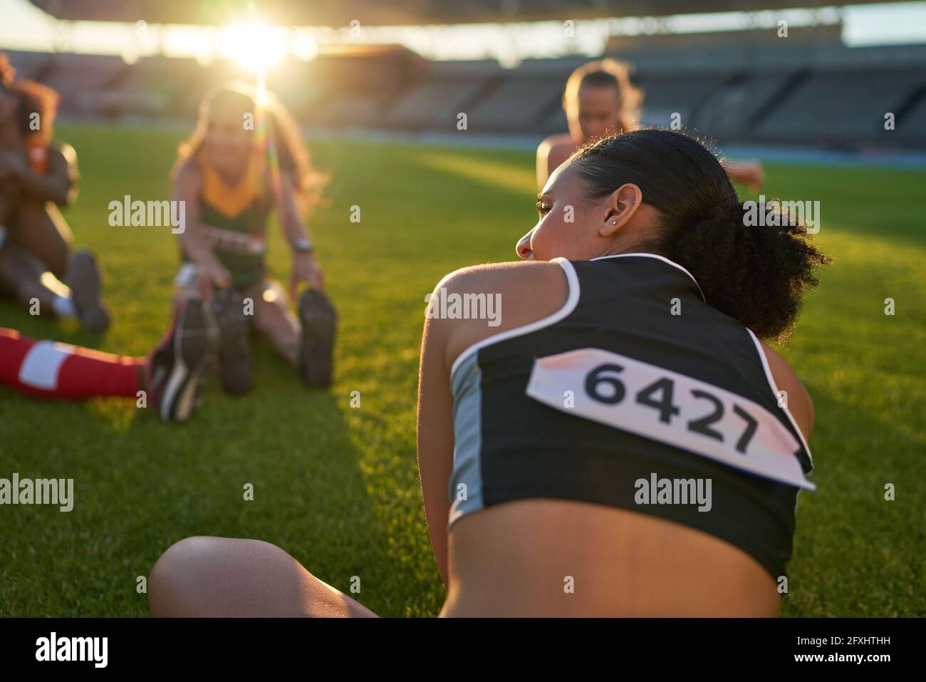 Female track and field athletes stretching before competition Stock