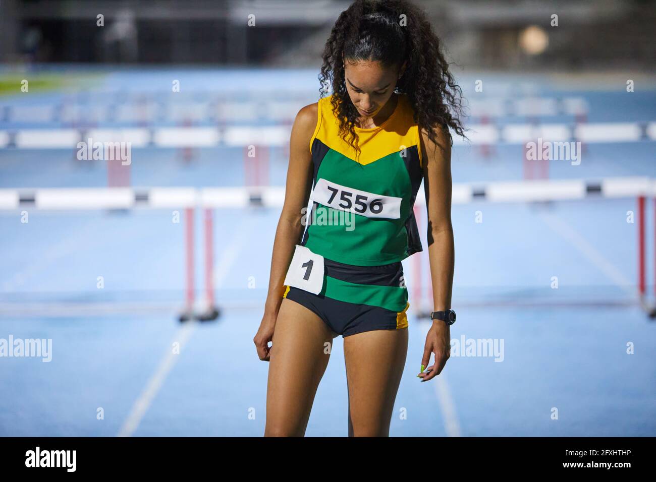 Female track and field athlete preparing for hurdle event Stock Photo