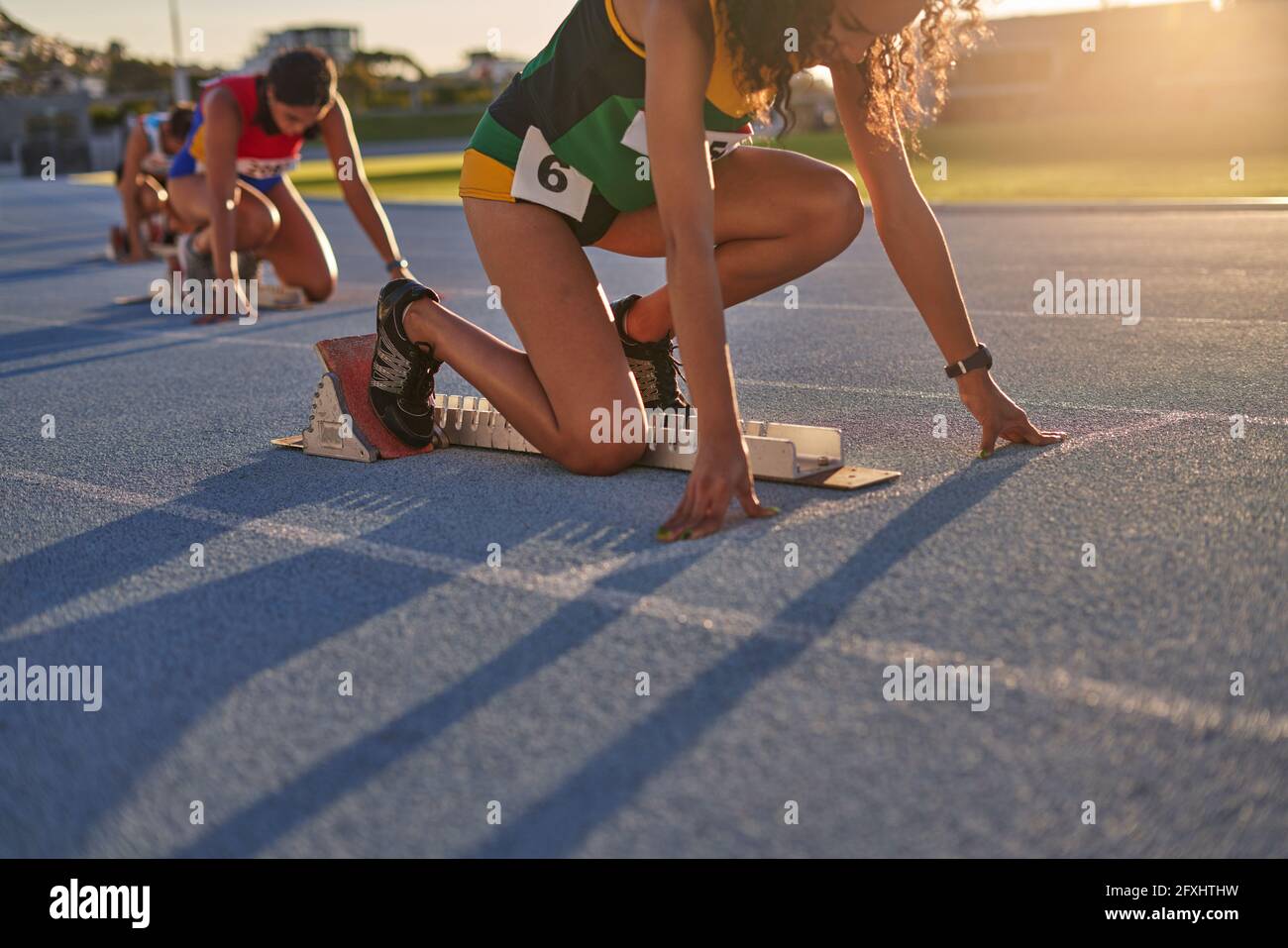 Female track and field athletes ready at starting blocks on track Stock