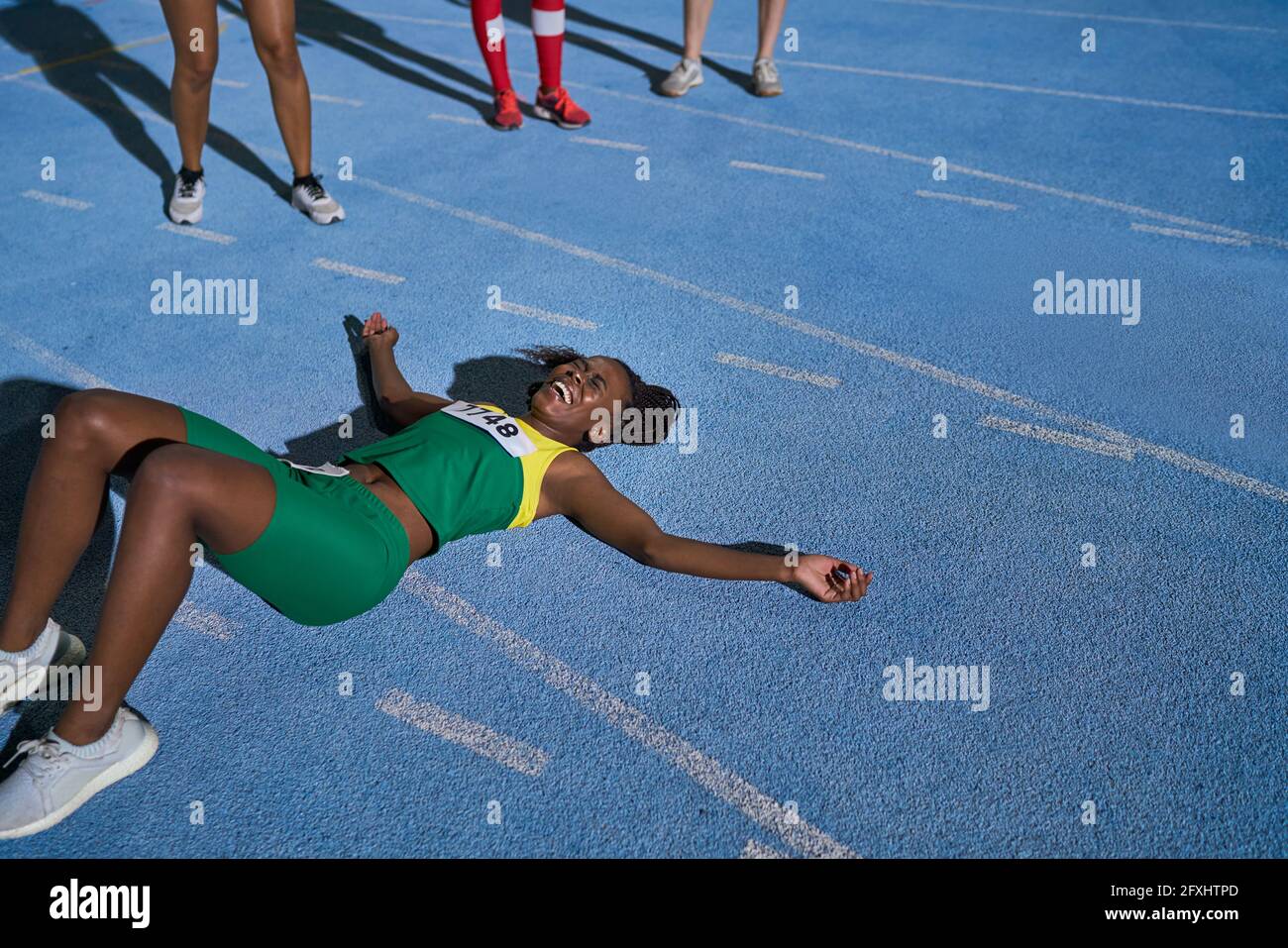 Tired track and field athlete laying on sunny track Stock Photo