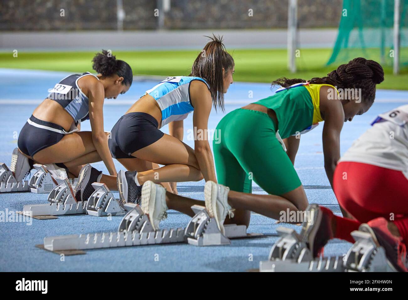 Female track and field athletes at starting blocks on track Stock Photo