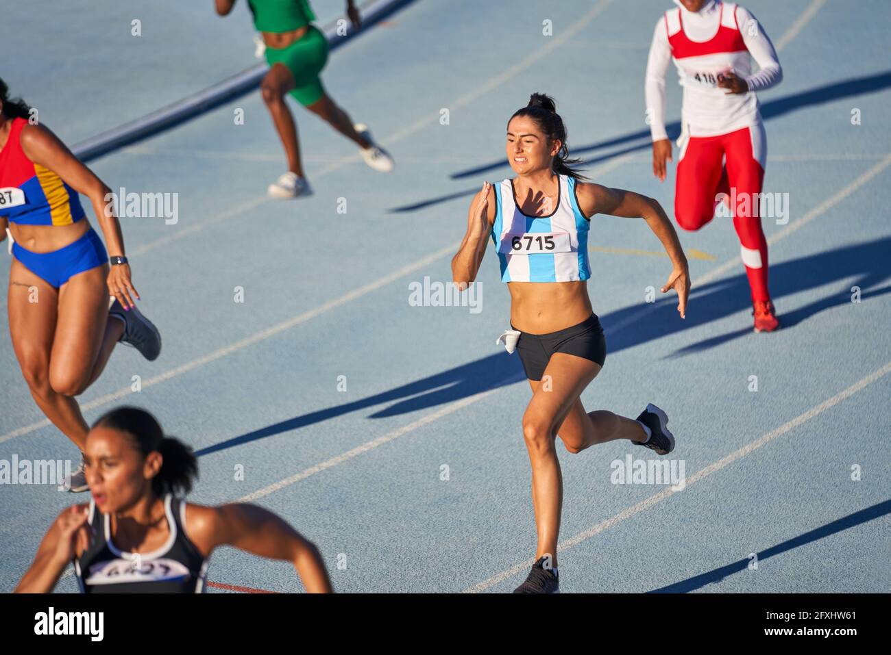 Female track and field athletes running in competition on sunny track