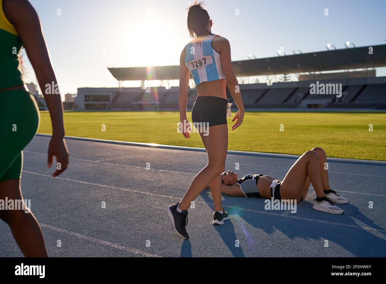 Tired female track and field athlete laying on track after competition Stock Photo