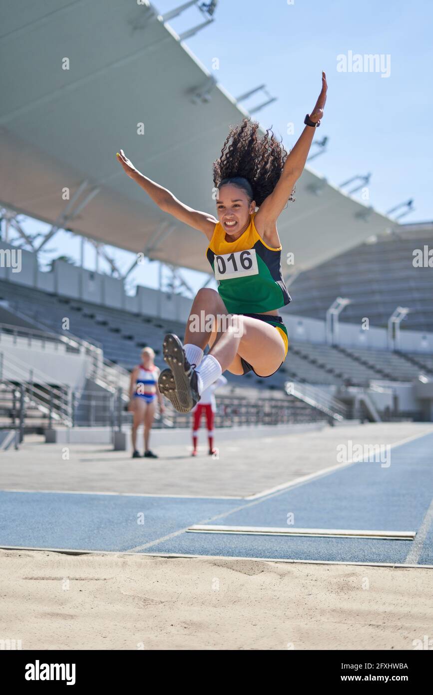 Female track and field athlete long jumping over sand Stock Photo Alamy