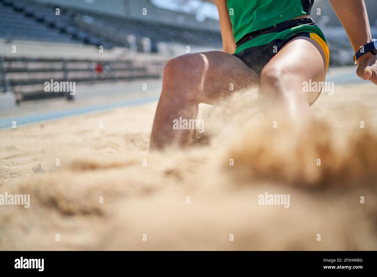 Female track and field long jumper landing in sand Stock Photo