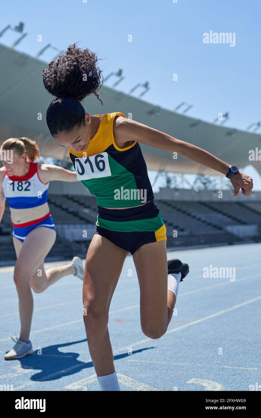 Female track and field athletes at competition finish line on track