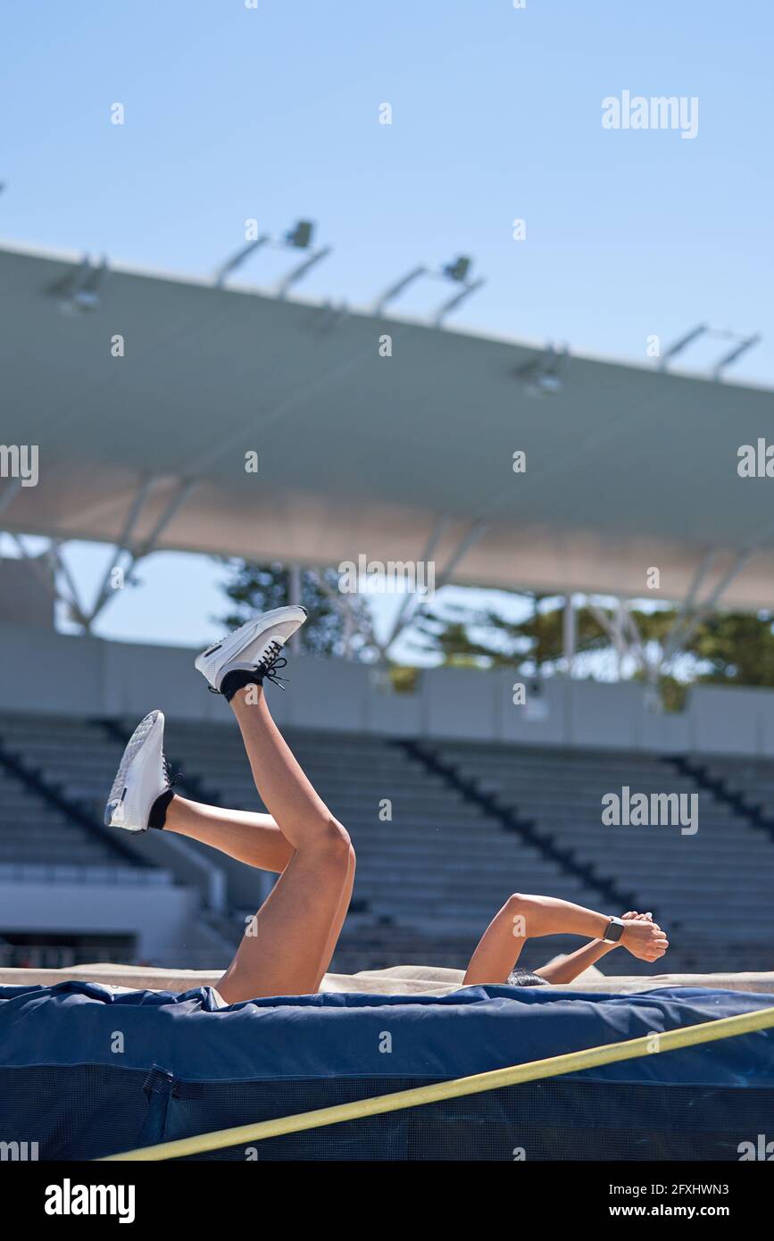 Female track and field athlete falling over high jump pole Stock Photo