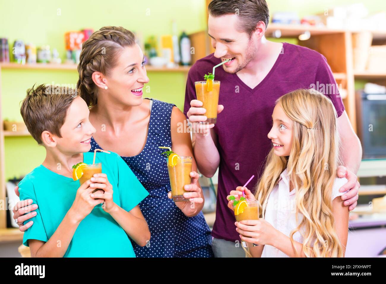 Parents and children drinking smoothie or juice in domestic kitchen