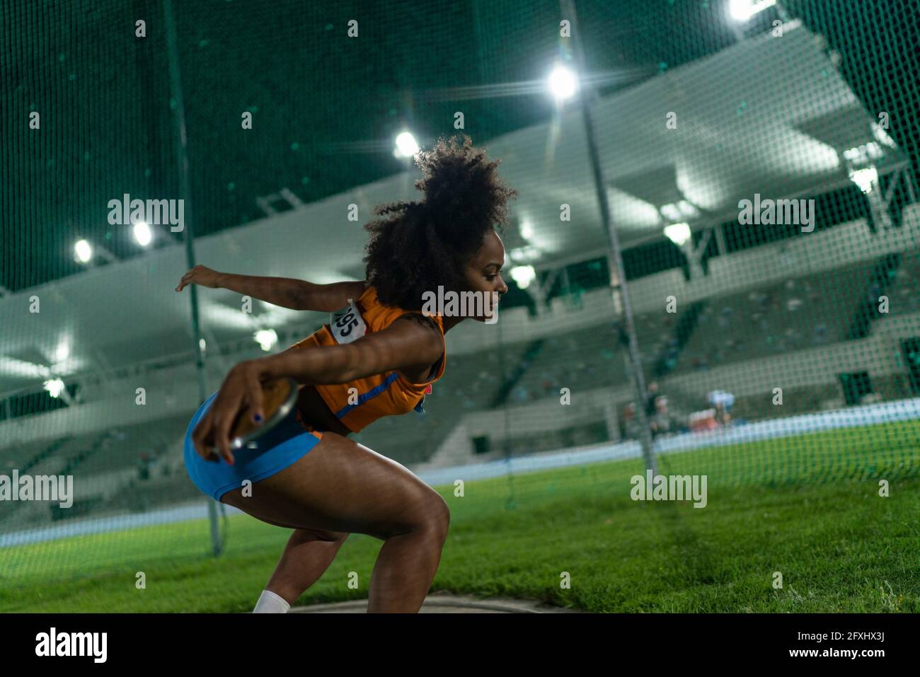 Female track and field athlete throwing discus at stadium competition