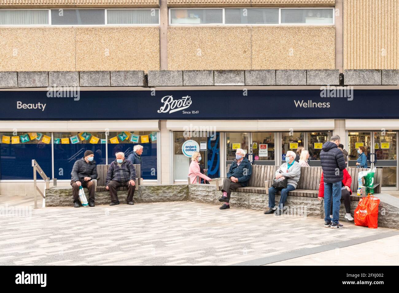 Elderly people wearing masks and sitting socially distanced on benches