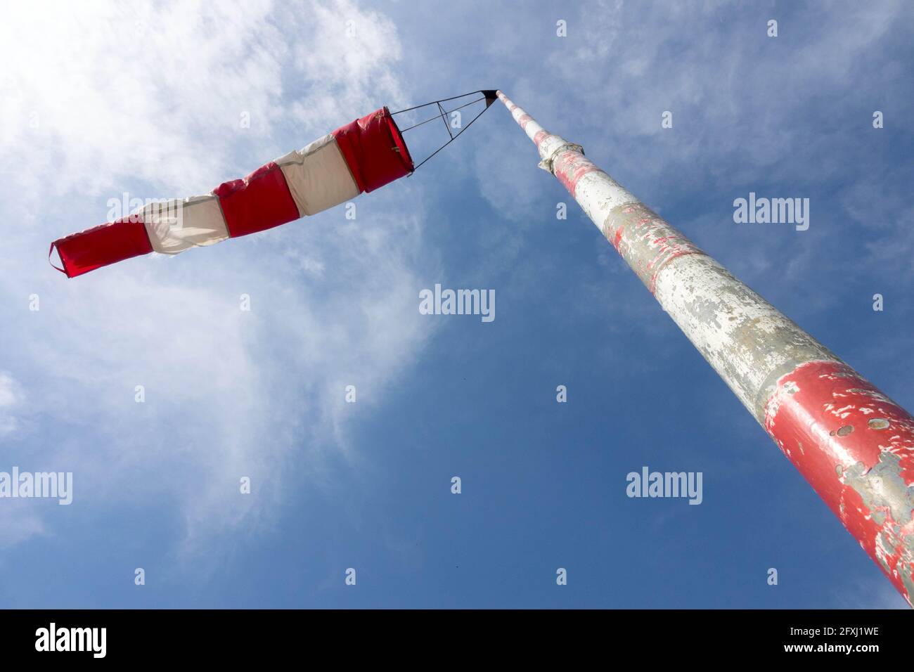 Wind sock on the end of stripped pole fluttering in the wind against sky Stock Photo