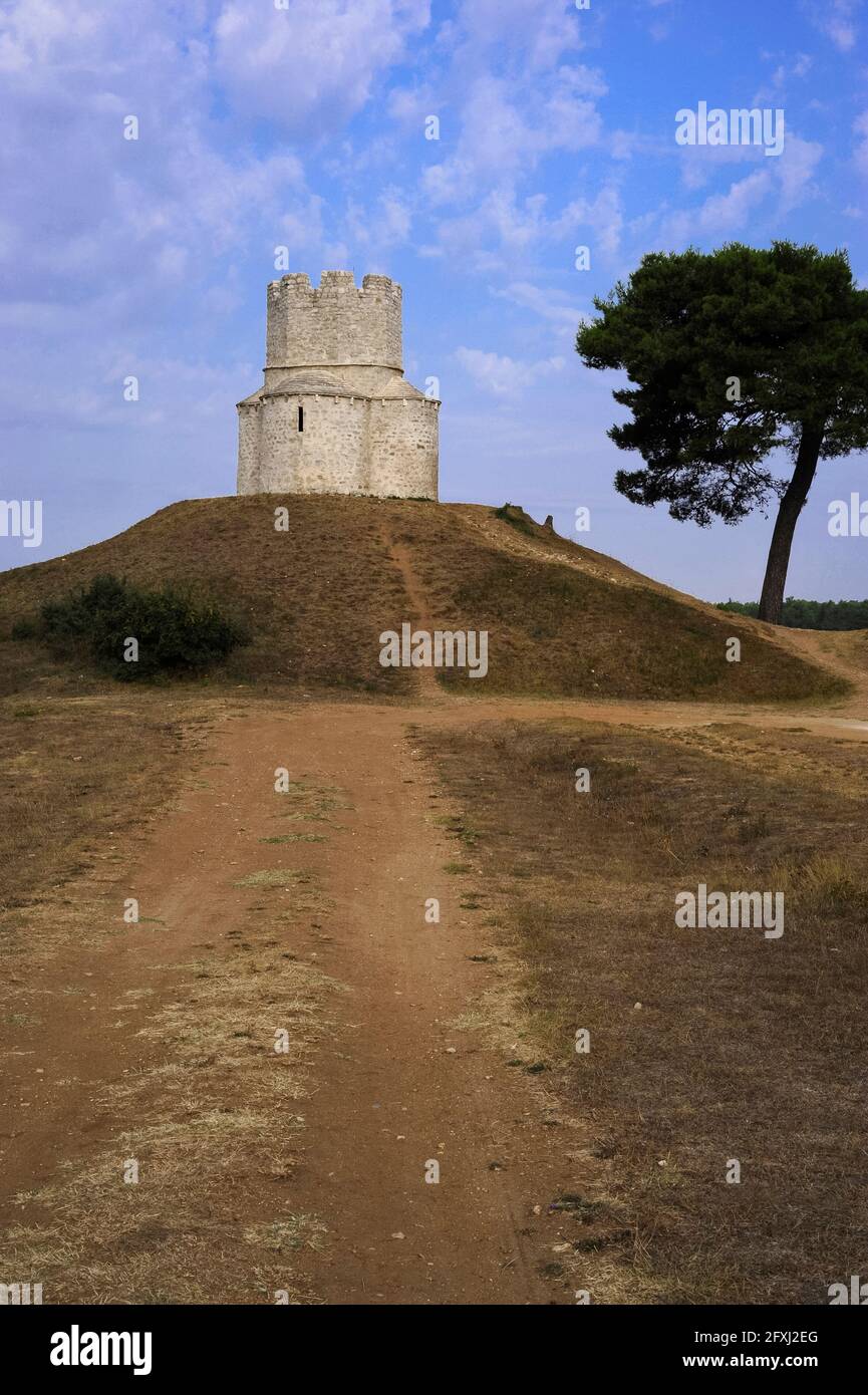 On a prehistoric burial mound, the medieval Church of Saint Nicholas, near Nin in Zadar County, North Dalmatia, Croatia.  The church was built in the late 1000s or early 1100s but the central battlemented watchtower was added much later, in the 1500s, when the church was fortified during conflict between the Kingdom of Croatia and the Ottoman Empire. Stock Photo