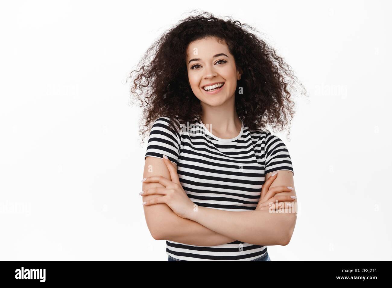 Image of brunette curly girl smiling confident, cross arms on chest ...
