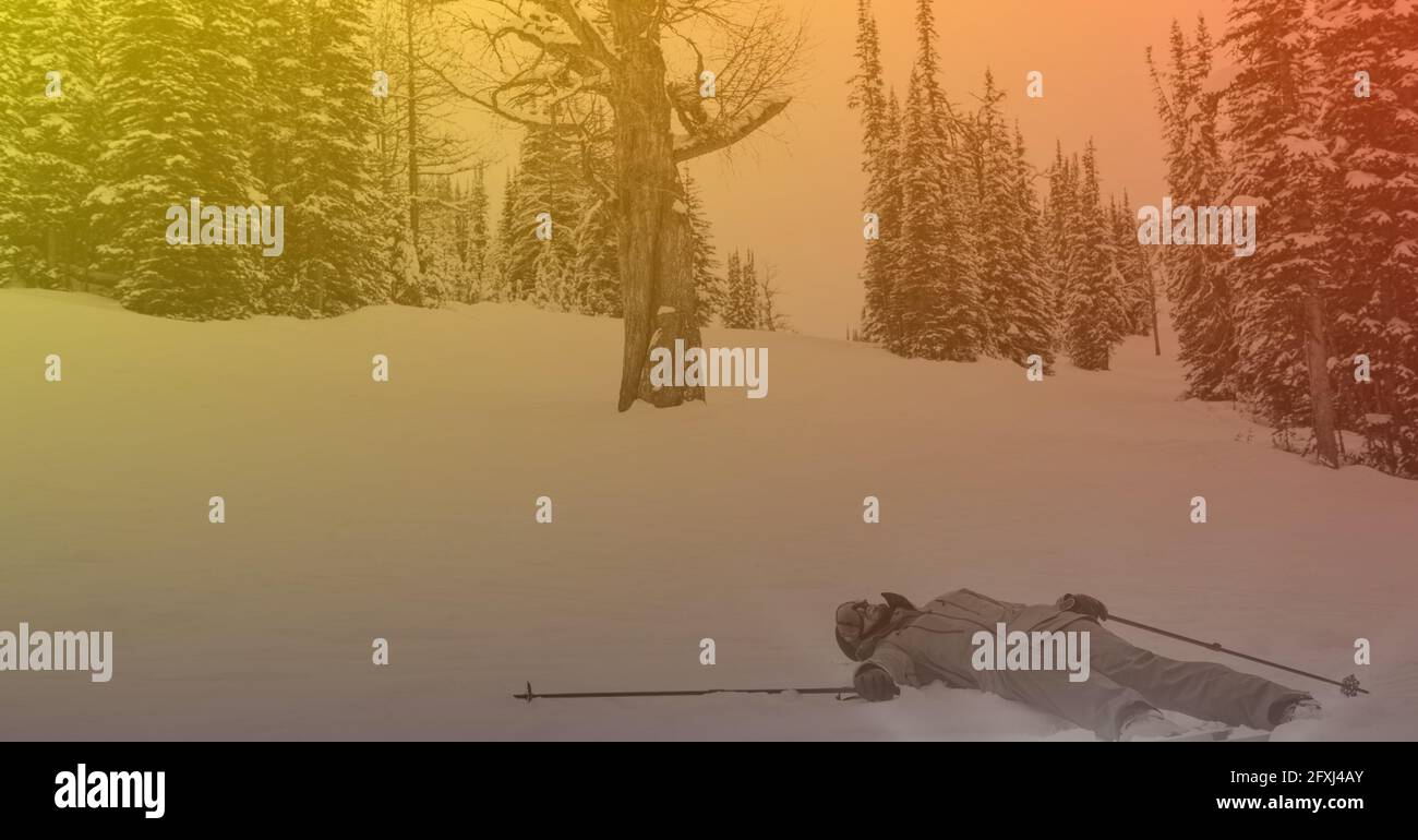 Composition of skier lying in snow in mountains with orange tint Stock Photo