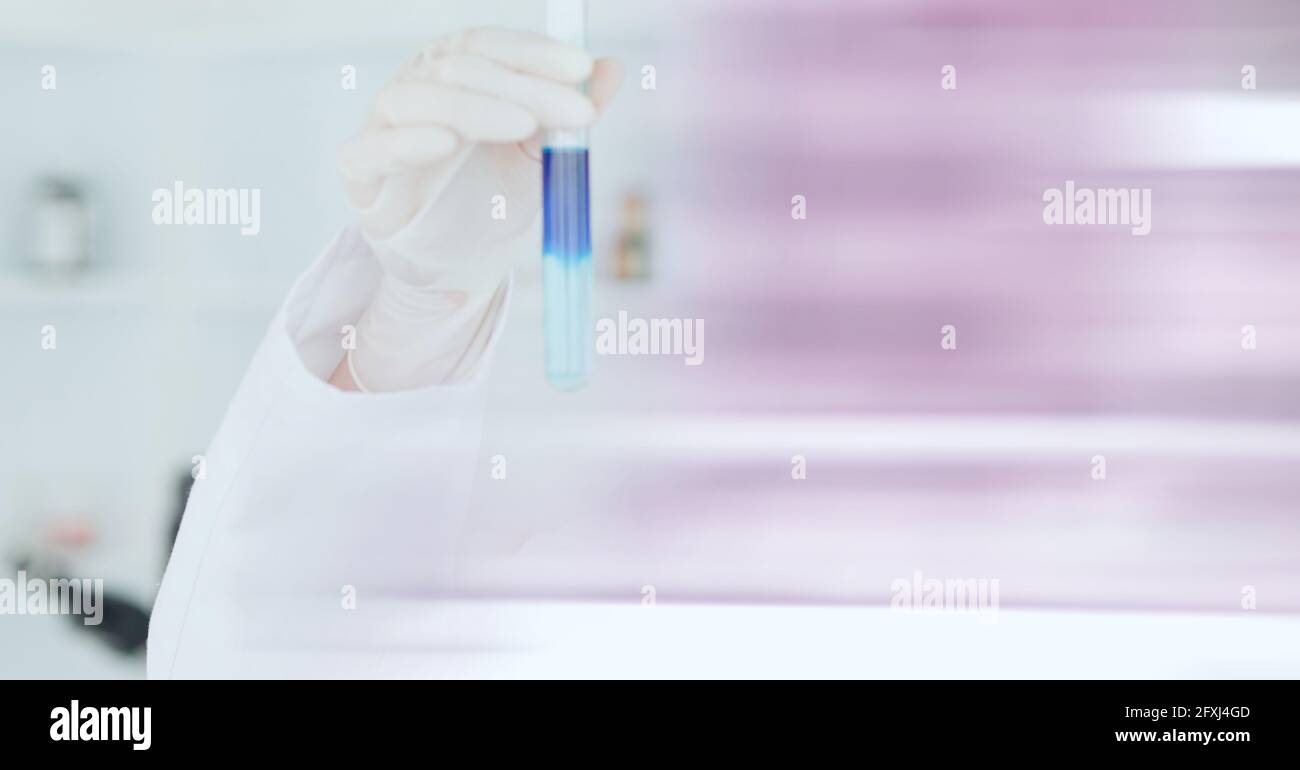 Composition of scientist holding test tube with blue liquid working in ...