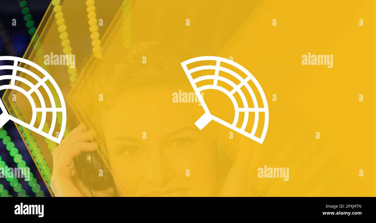 Composition of aerial antenna icons on yellow over smiling woman in headphones and green dot stripes Stock Photo