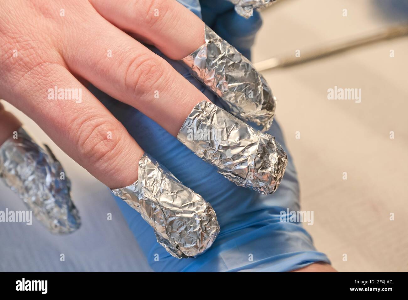 Foil on woman's nails during manicure. Fingernails covered with foil