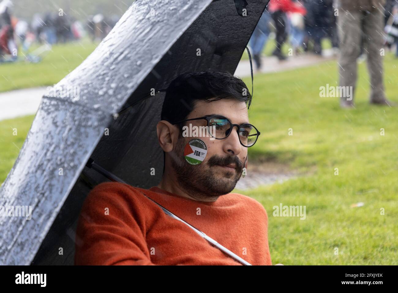 Portrait of protester sheltering from rain with umbrella, Free Palestine Protest, Hyde Park, London, 22 May 2021 Stock Photo