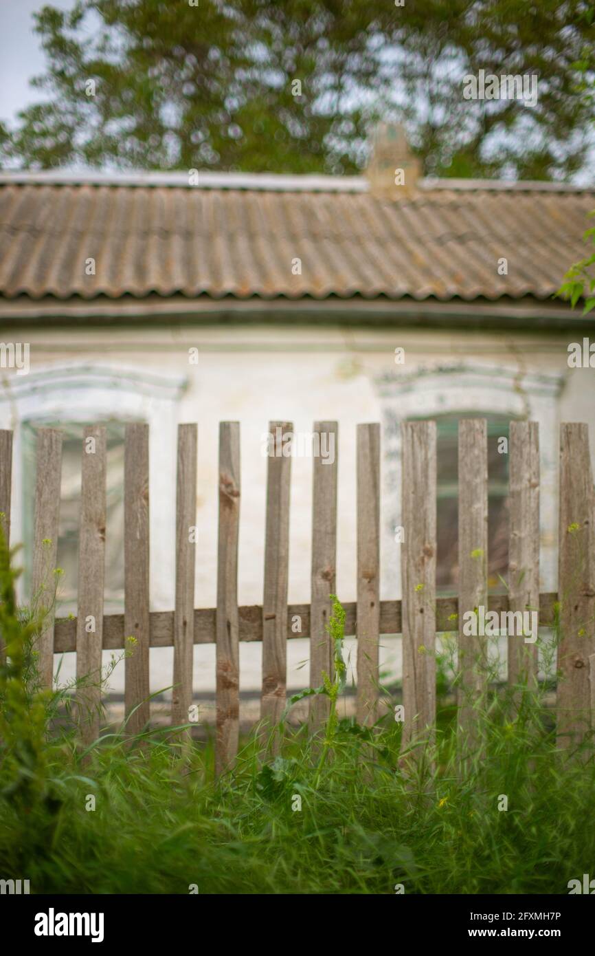 Old picket fence. Rural house in blurred background. Stock Photo